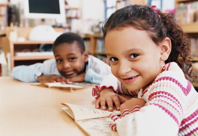 children sitting at desk with their books 